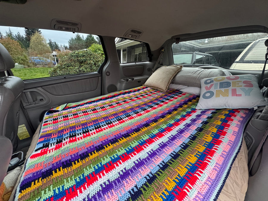 suggesting winter travel. RV rental and snow-covered trees highlight outdoor adventure options.|Colorful crochet blanket & pillows on a bed in a vehicle