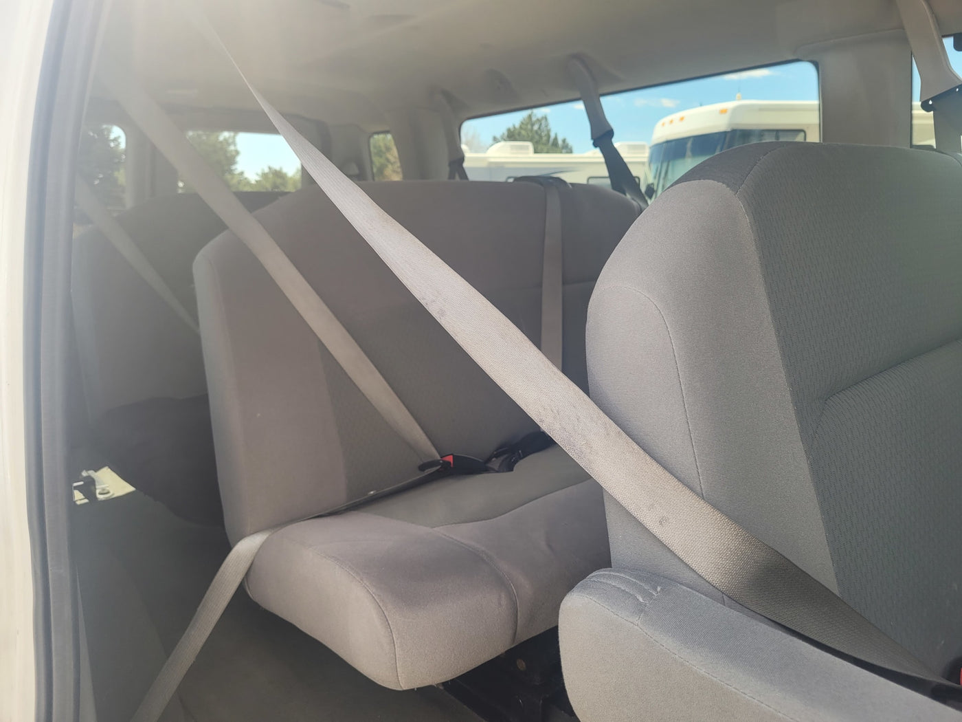Interior view of an RV rental, featuring gray rear seats and seatbelts, with other RVs parked outside. — photo 10