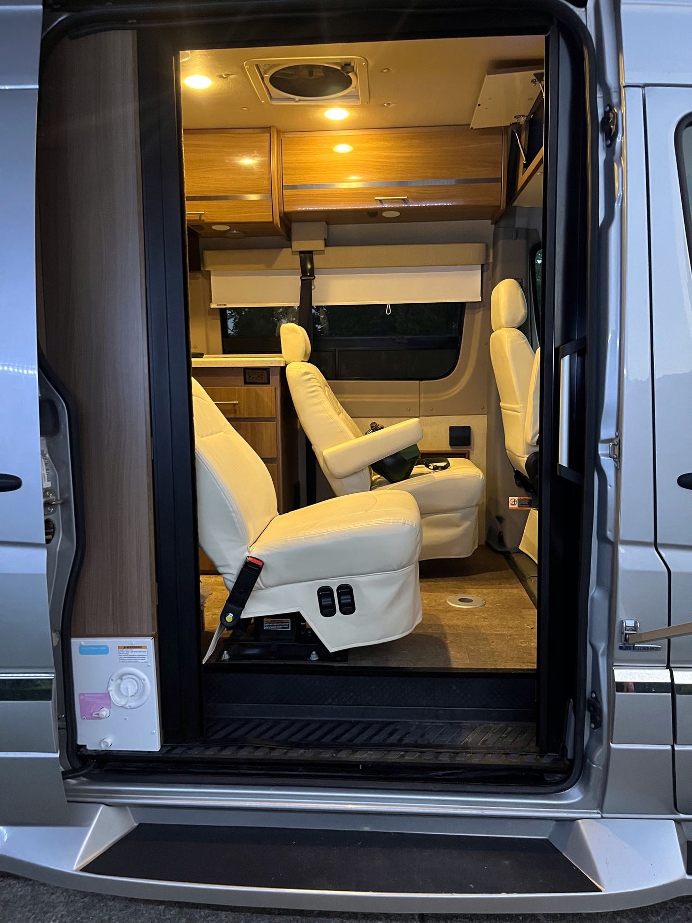 revealing separate fridge and freezer compartments with shelving and door bins.|Winnebago Era RV rental interior: spacious cabin with dashboard