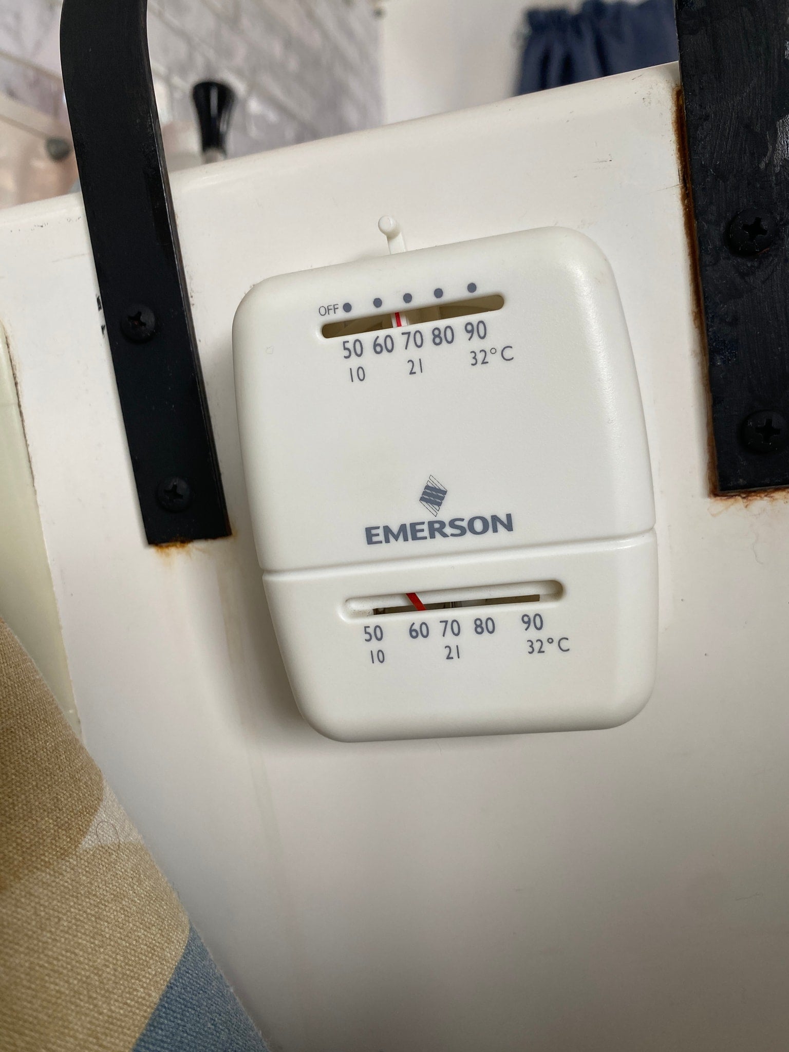 Emerson thermostat in an RV rental. Dual sliders adjust climate control, showing Fahrenheit/Celsius settings on the white unit.