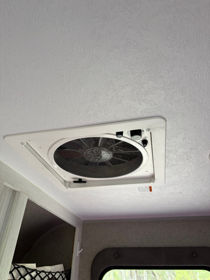 RV rental: Ceiling-mounted white vent fan with accessible speed/direction controls against a textured white ceiling.