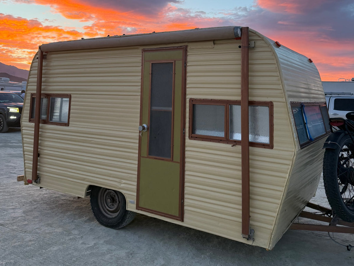 ready for your next adventure.|Vintage beige RV rental under a stunning desert sunset. This travel trailer features a green door — photo 2