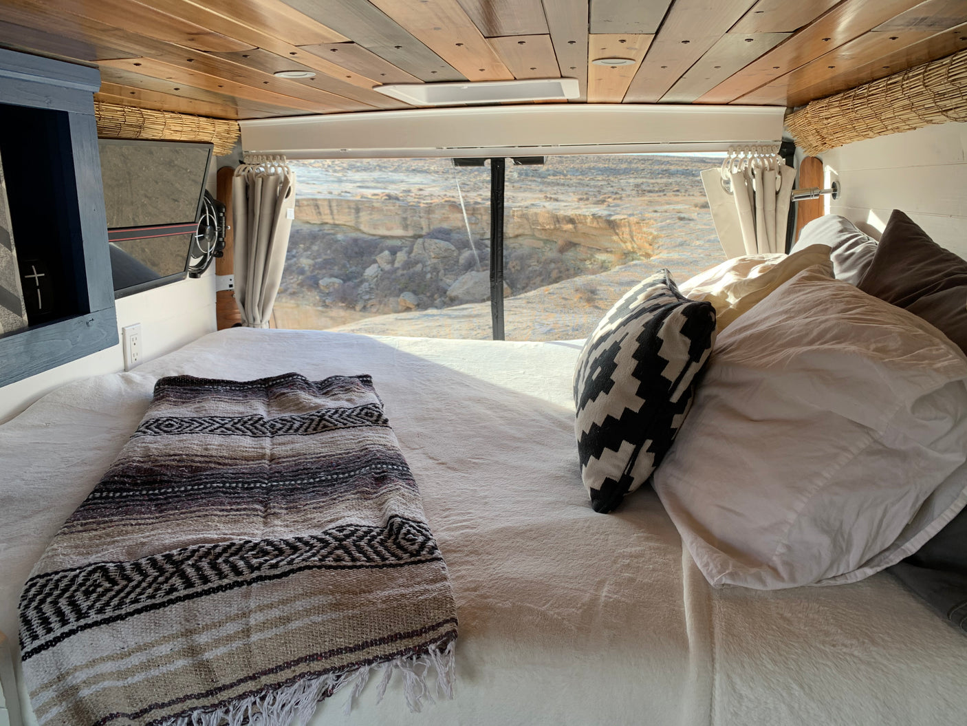 Cozy RV rental interior with a comfortable bed and stunning desert views through the back window. Perfect for adventure.