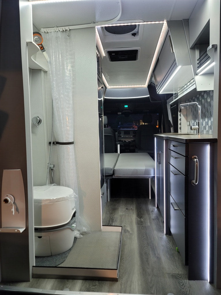 on a scenic path through tall reeds under a clear blue sky.|A white rv rental camper van with its side door open