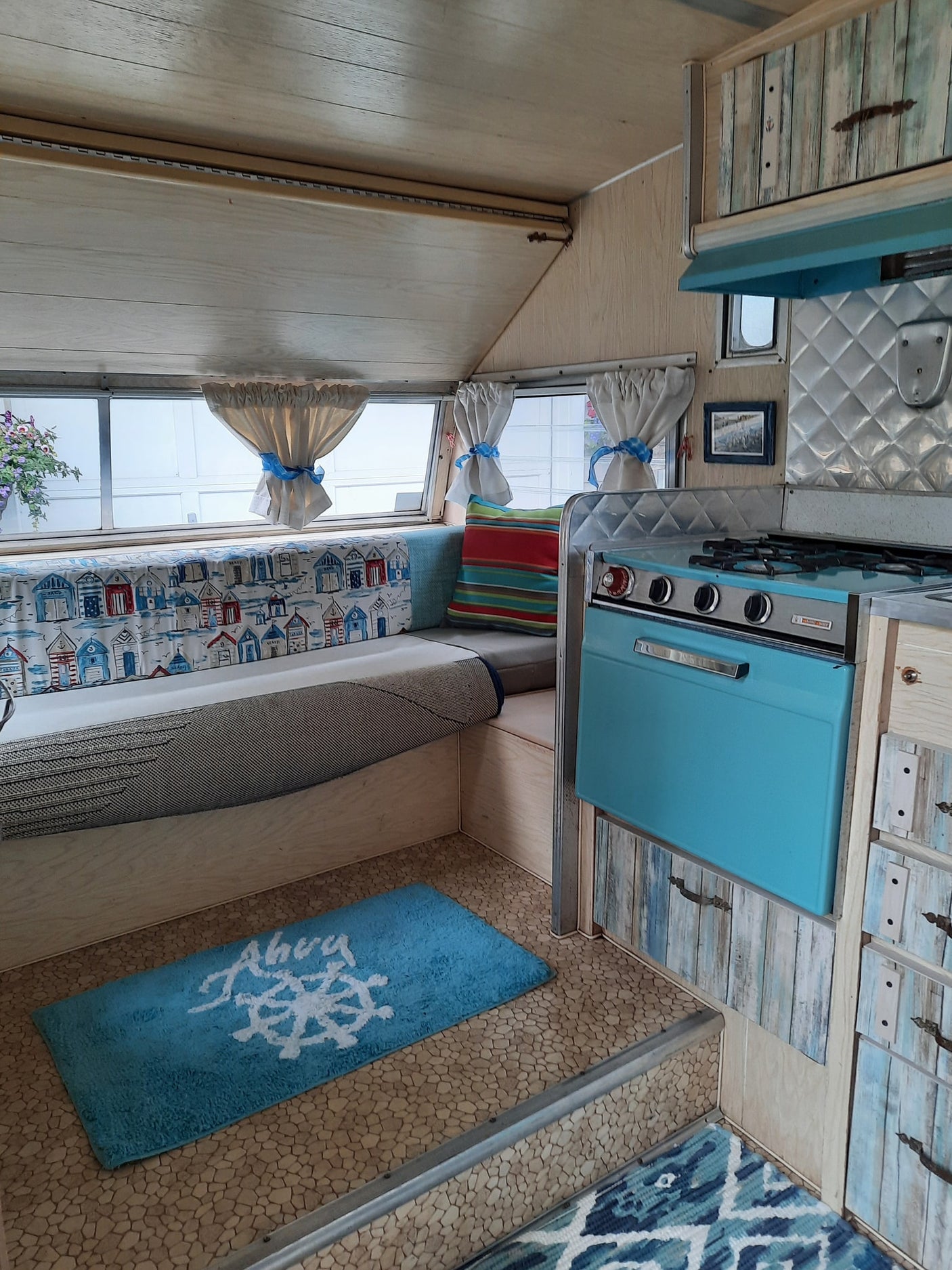 RV rental: Charming interior view with a retro teal stove, wooden cabinets, and cozy nautical-themed decor.