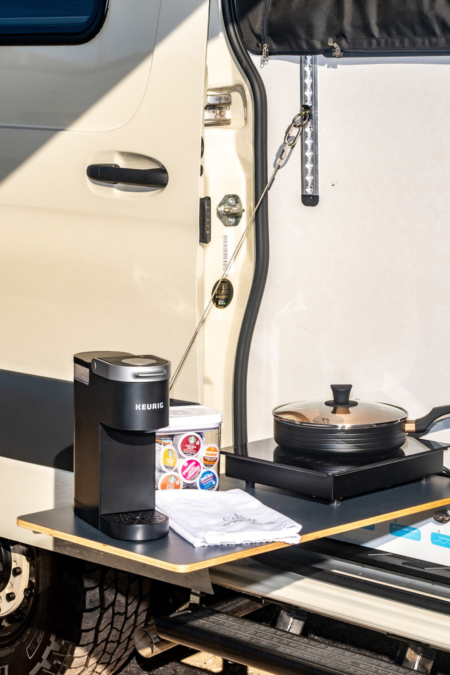 RV rental outdoor kitchen featuring a Keurig coffee maker, cooktop, and pan. Perfect for adventurers on the go.