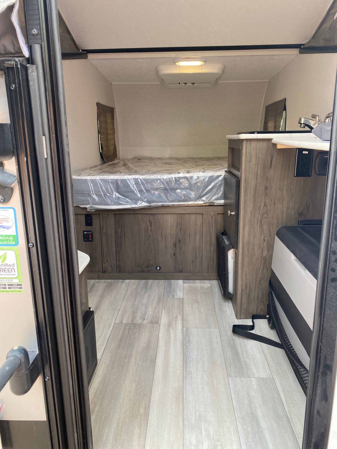 Inside a cozy rv rental with a bed, kitchenette, and wood finishes, ideal for compact travel.