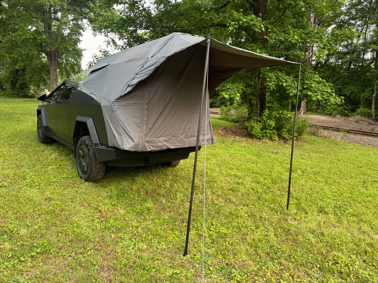 perfect for an rv rental adventure in nature.|Dark grey Tesla Cybertruck with an attached rear tent