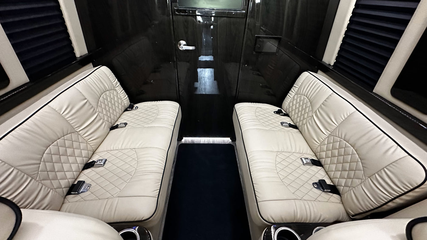 Luxurious RV rental interior with opposing cream quilted seats, dark paneling, and privacy blinds. Ideal for comfortable travel.