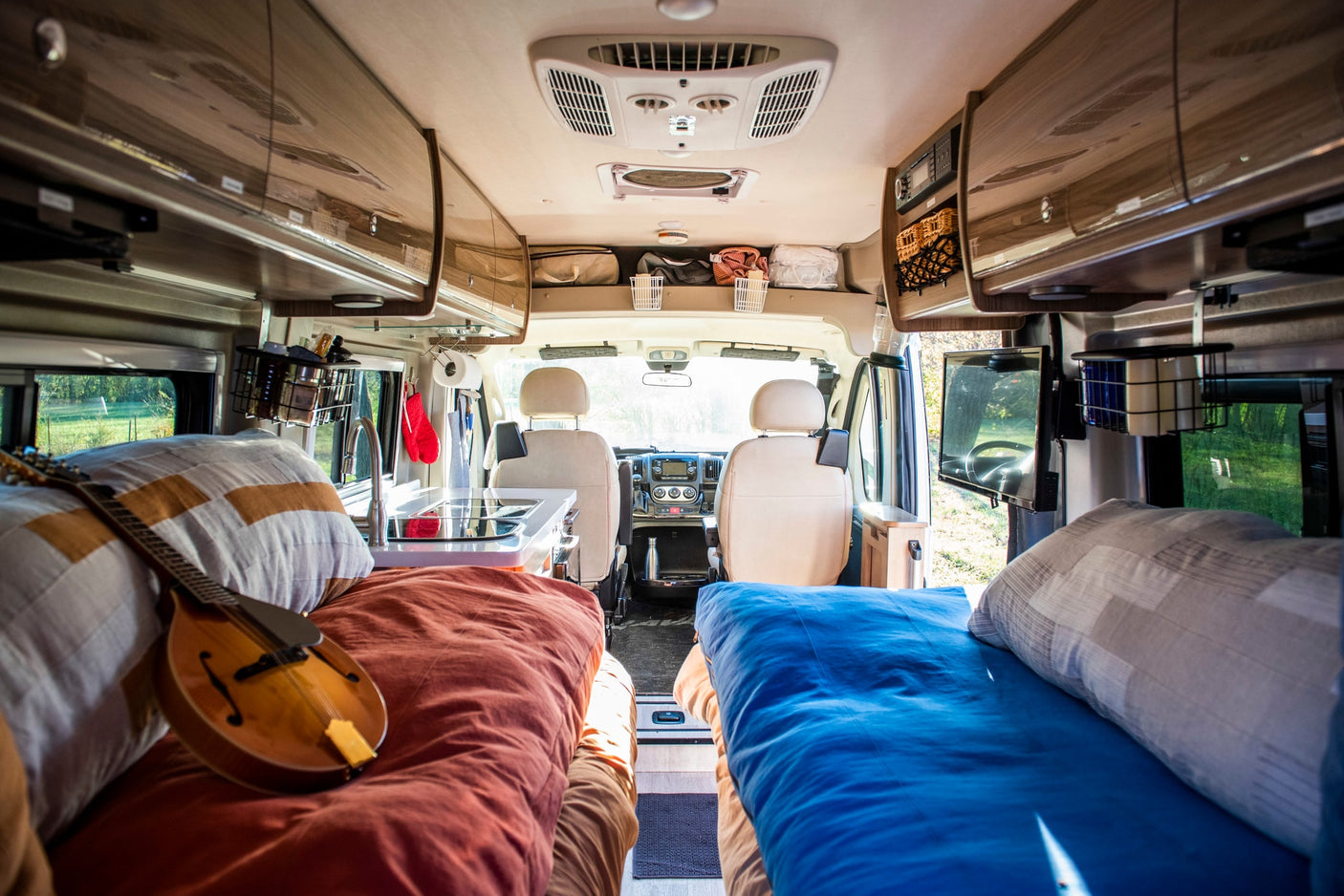 Spacious RV rental interior with beds (one with mandolin), kitchen, & driver's cabin view. Ready for your adventure.