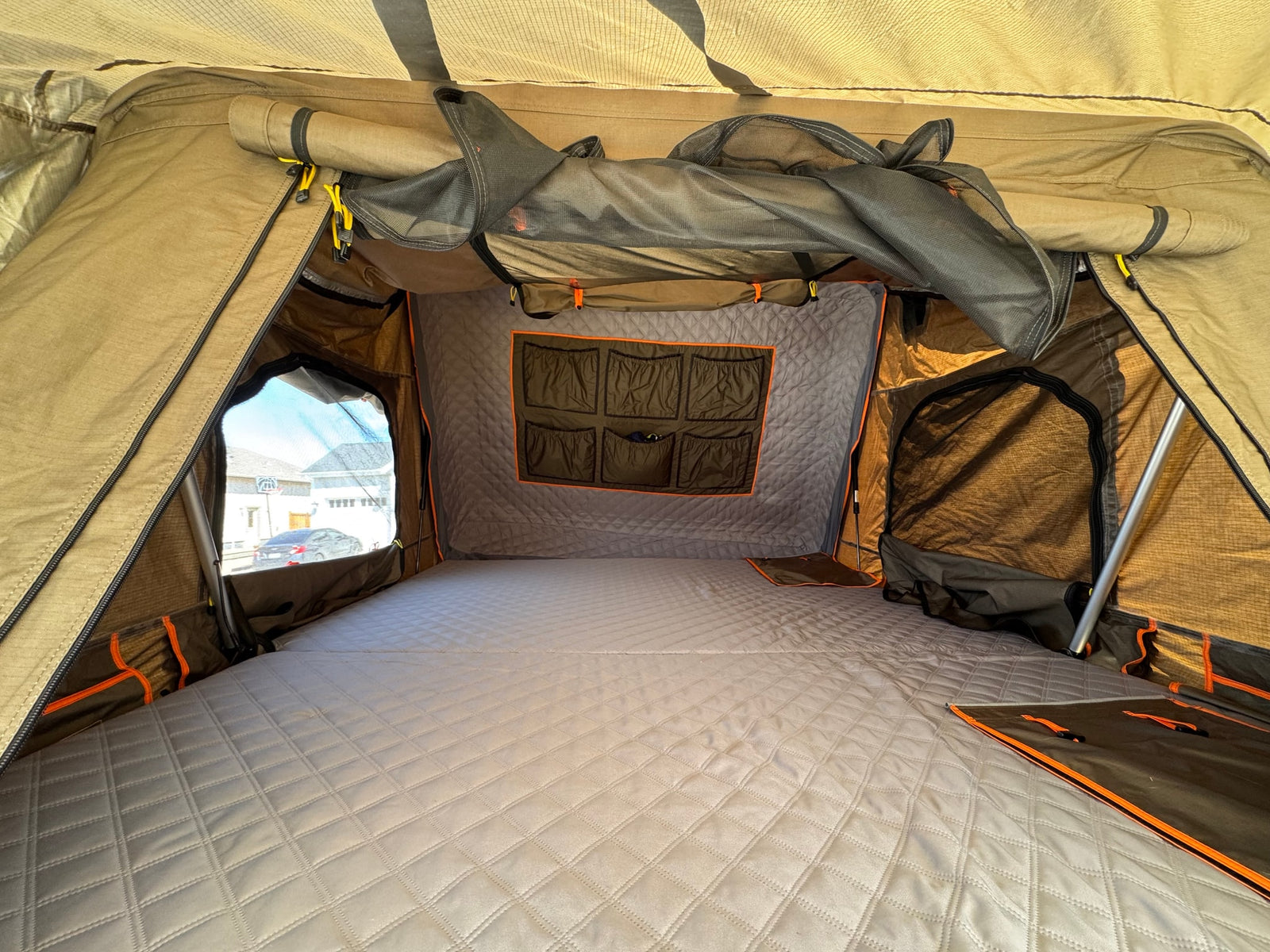 Spacious camping tent interior: quilted sleeping pad, window view, and storage pockets. Great for **RV rental** adventures.