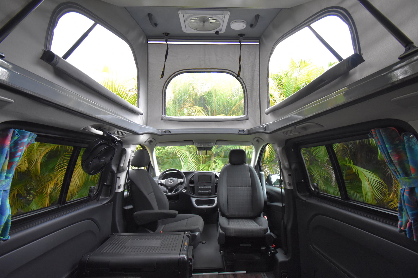 Inside a comfortable rv rental camper van: pop-top, front seats, and lush tropical views for your next adventure.