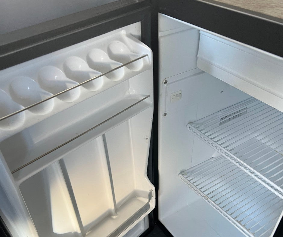 This clean, empty refrigerator in an RV rental features door storage for eggs and other items, plus wire shelves.