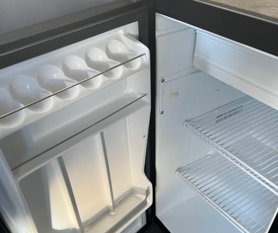 This clean, empty refrigerator in an RV rental features door storage for eggs and other items, plus wire shelves.