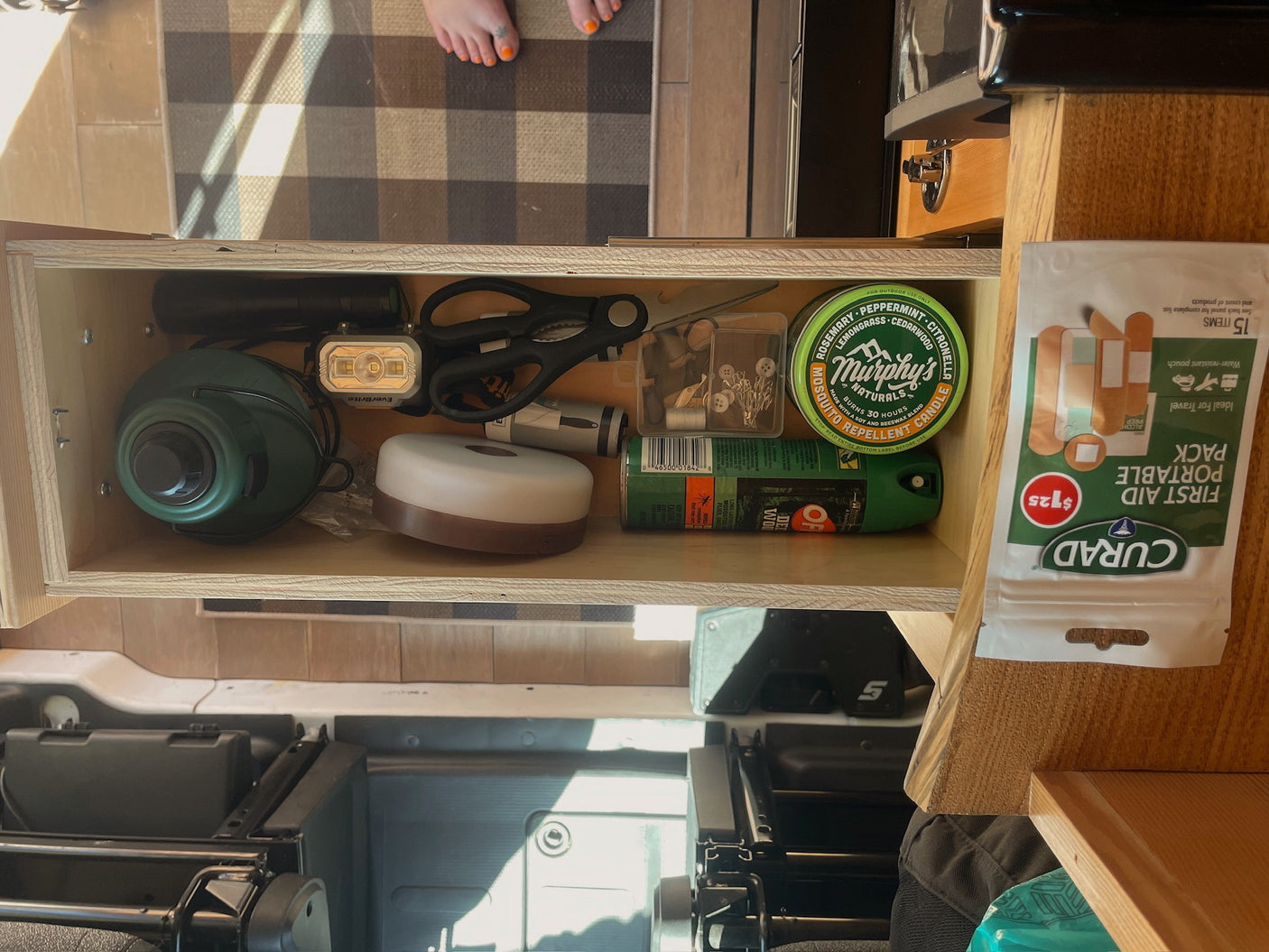RV rental essentials: a well-organized drawer stocked with flashlights, bug repellent, first aid, and sewing supplies for travel readiness.