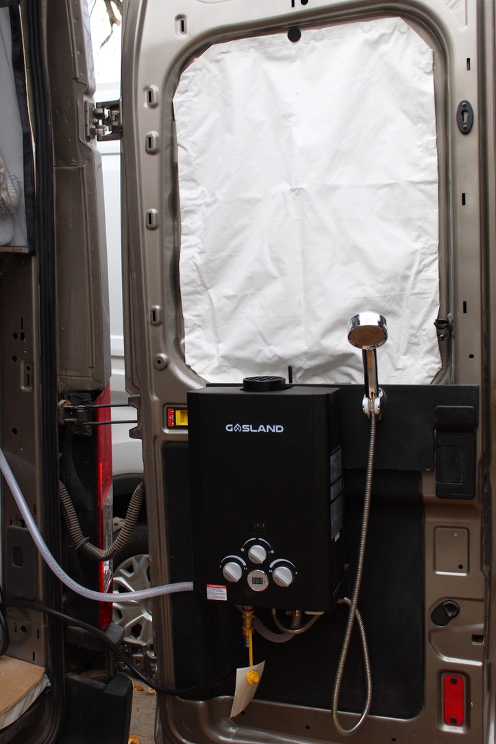 Gasland portable tankless water heater on an RV rental van door, great for camping showers.