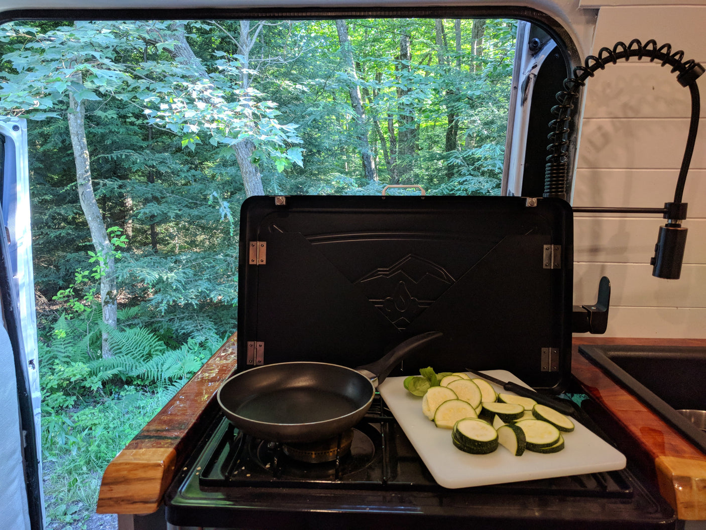 Cooking fresh zucchini in an RV rental kitchen with a beautiful forest view. Ideal for nature lovers & camping trips.