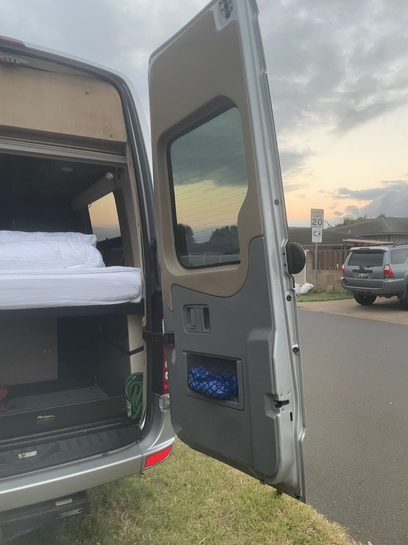 Open RV rental rear reveals a cozy bed and storage. Perfect for van life adventures.