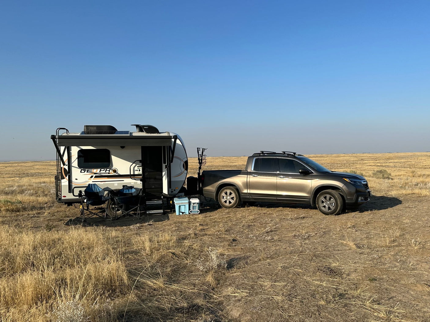 A tan truck next to a white GEOPRO rv rental