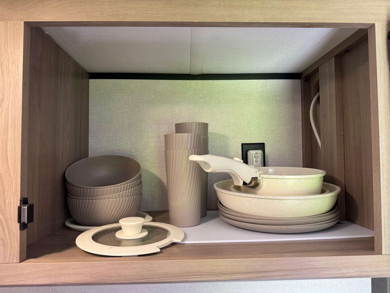 RV rental: Compact cabinet neatly storing stackable bowls, cups, pots, pans, and plates for your adventures.