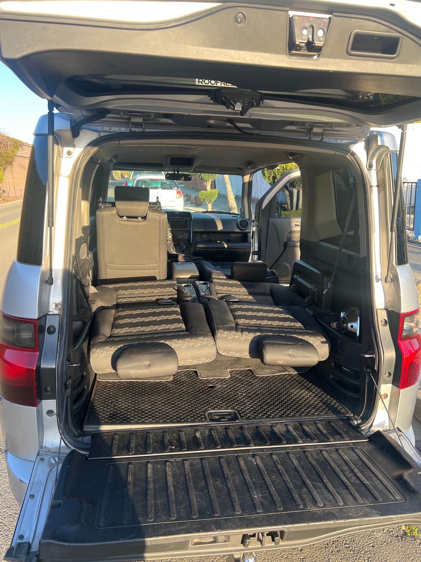 Open tailgate of a spacious vehicle with seats folded flat, ready for car camping or an rv rental.
