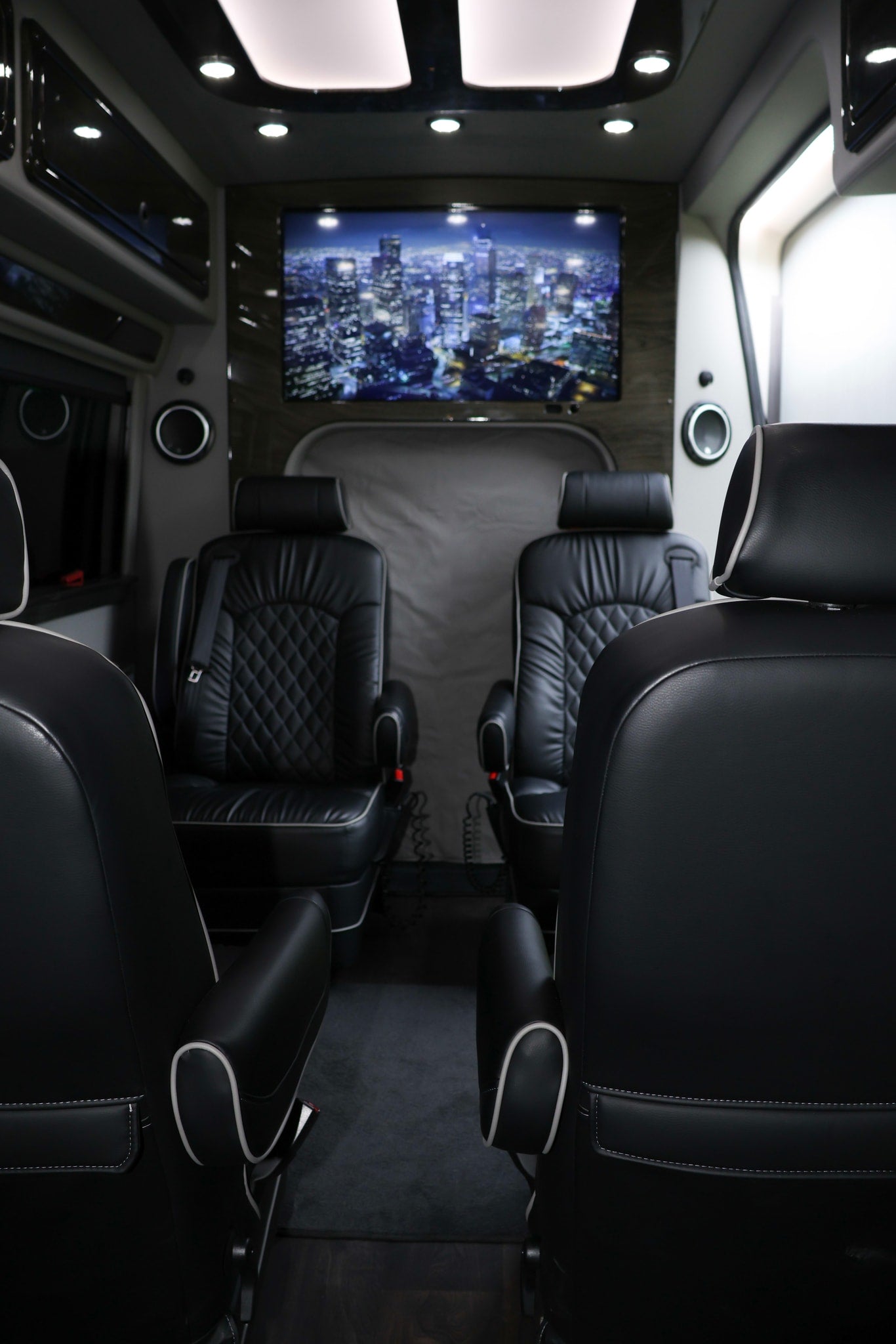 Luxury RV rental interior: black leather captain's chairs, a large TV displaying a cityscape, and mood lighting for comfort.