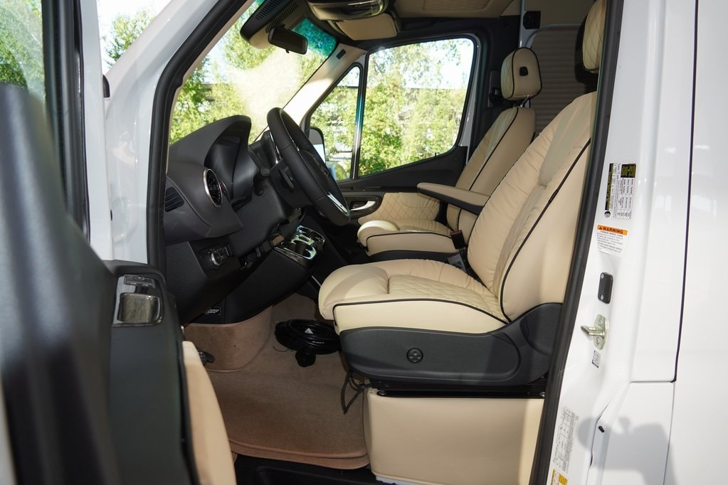 perfect for comfortable travel.|Explore this opulent rv rental: custom van interior with quilted cream leather captain's chairs & controls.|Experience luxury in this RV rental. Sumptuous cream seats
