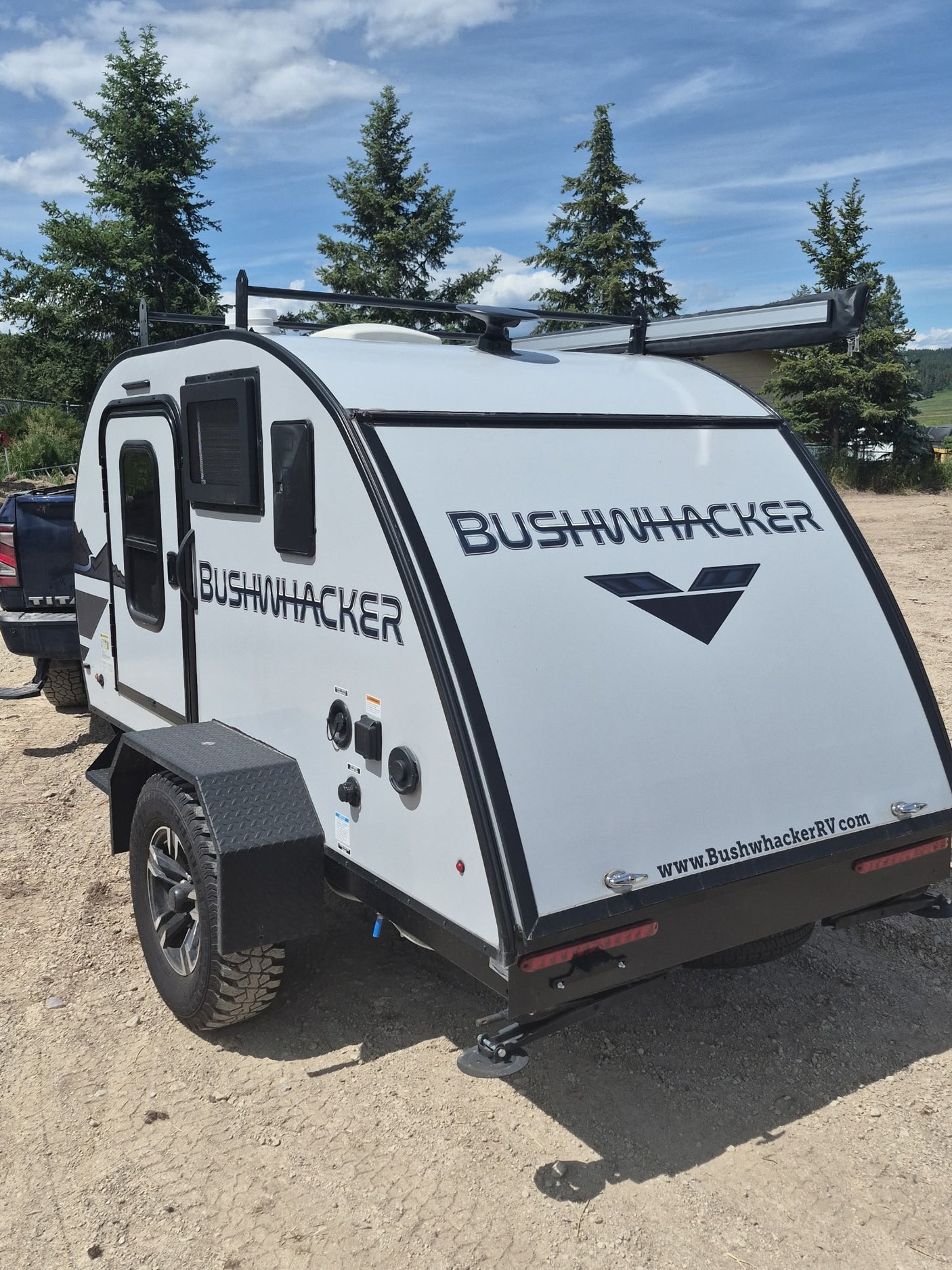 ready for camping adventures.|Light gray Bushwhacker teardrop travel trailer on gravel. This compact RV rental