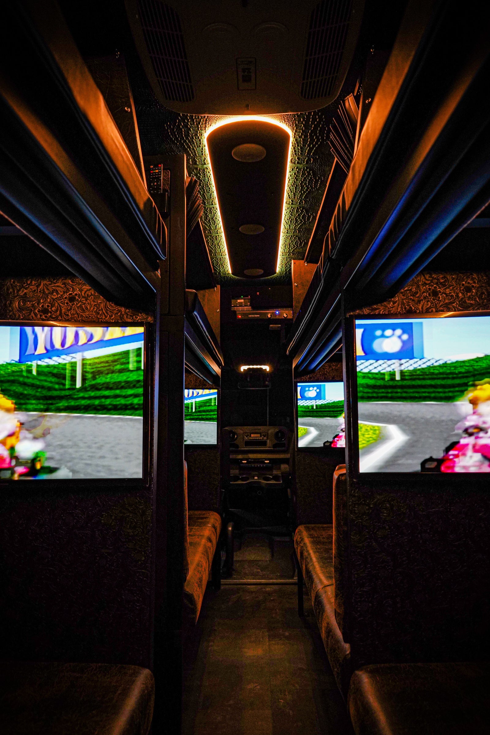 Experience mobile gaming in this custom RV rental, featuring multiple screens playing Mario Kart and plush seating inside.