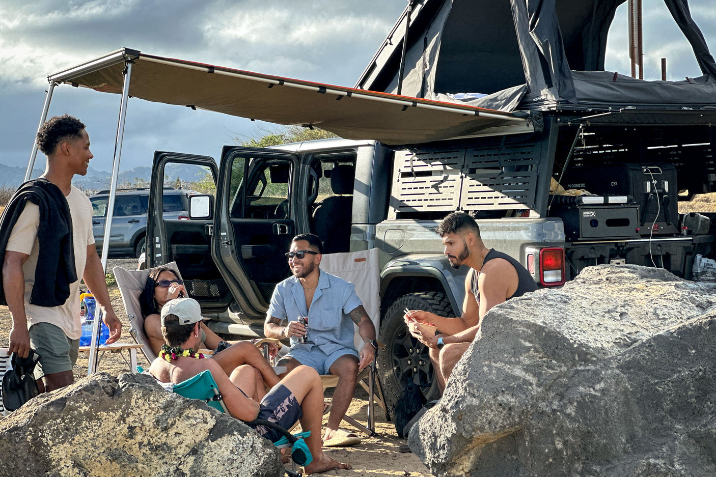 An RV rental Jeep Gladiator with rooftop tent and awning provides comfort for friends enjoying an outdoor glamping trip.