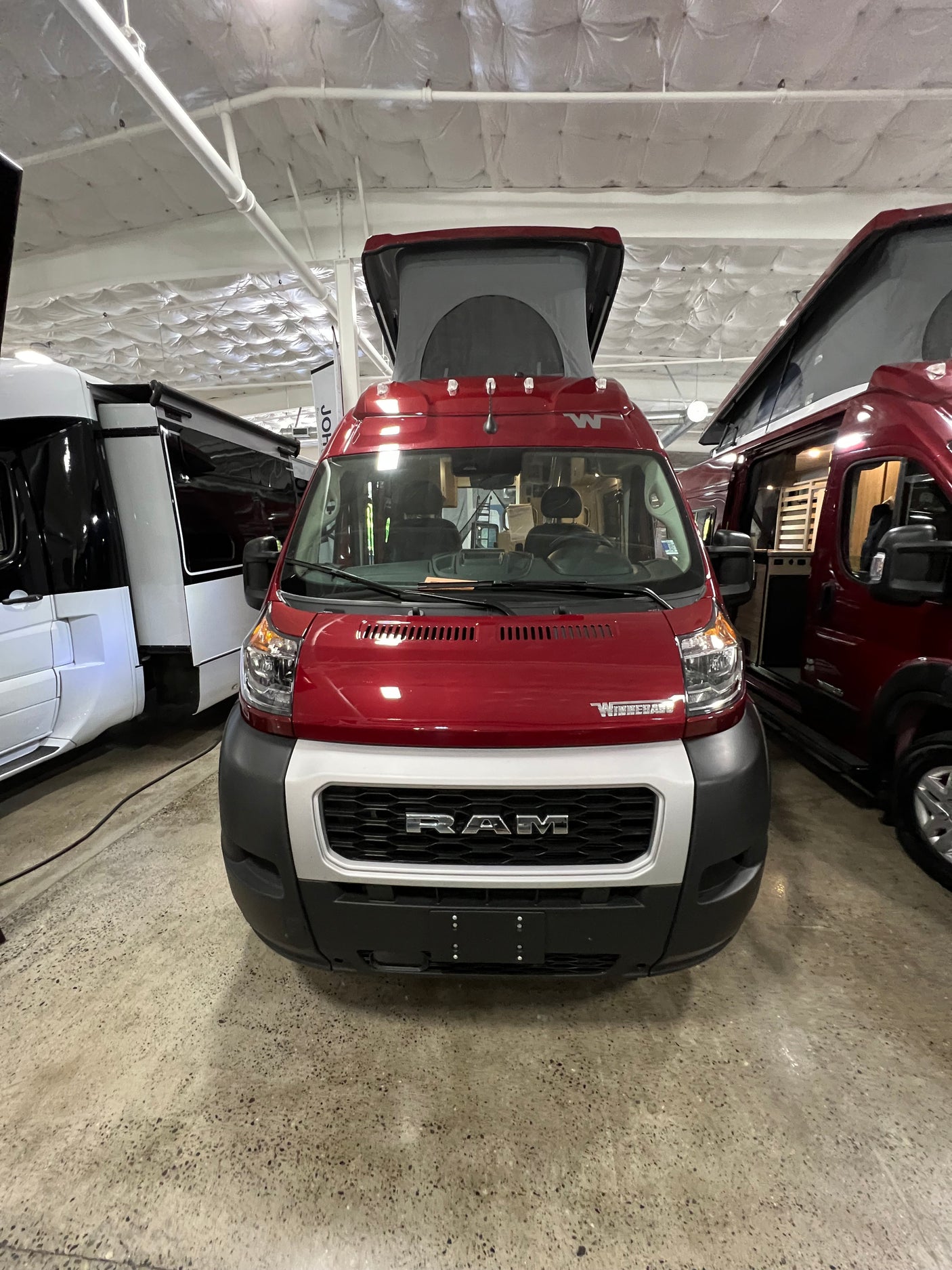 Red Winnebago Ram ProMaster pop-top camper van, ideal for your next RV rental adventure.