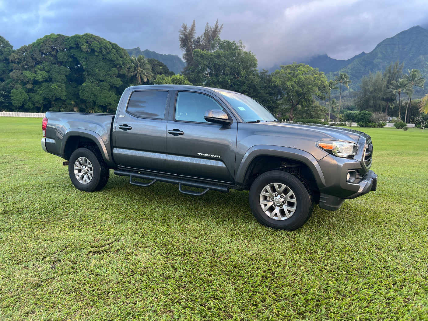 This gray pickup truck parked on lush Hawaiian grass with misty mountains hints at epic journeys, like those with an RV rental.