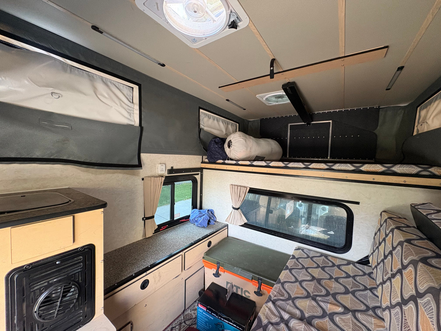 Explore this cozy RV rental interior: kitchenette, sleeping bunk, and comfortable seating for your next adventure.