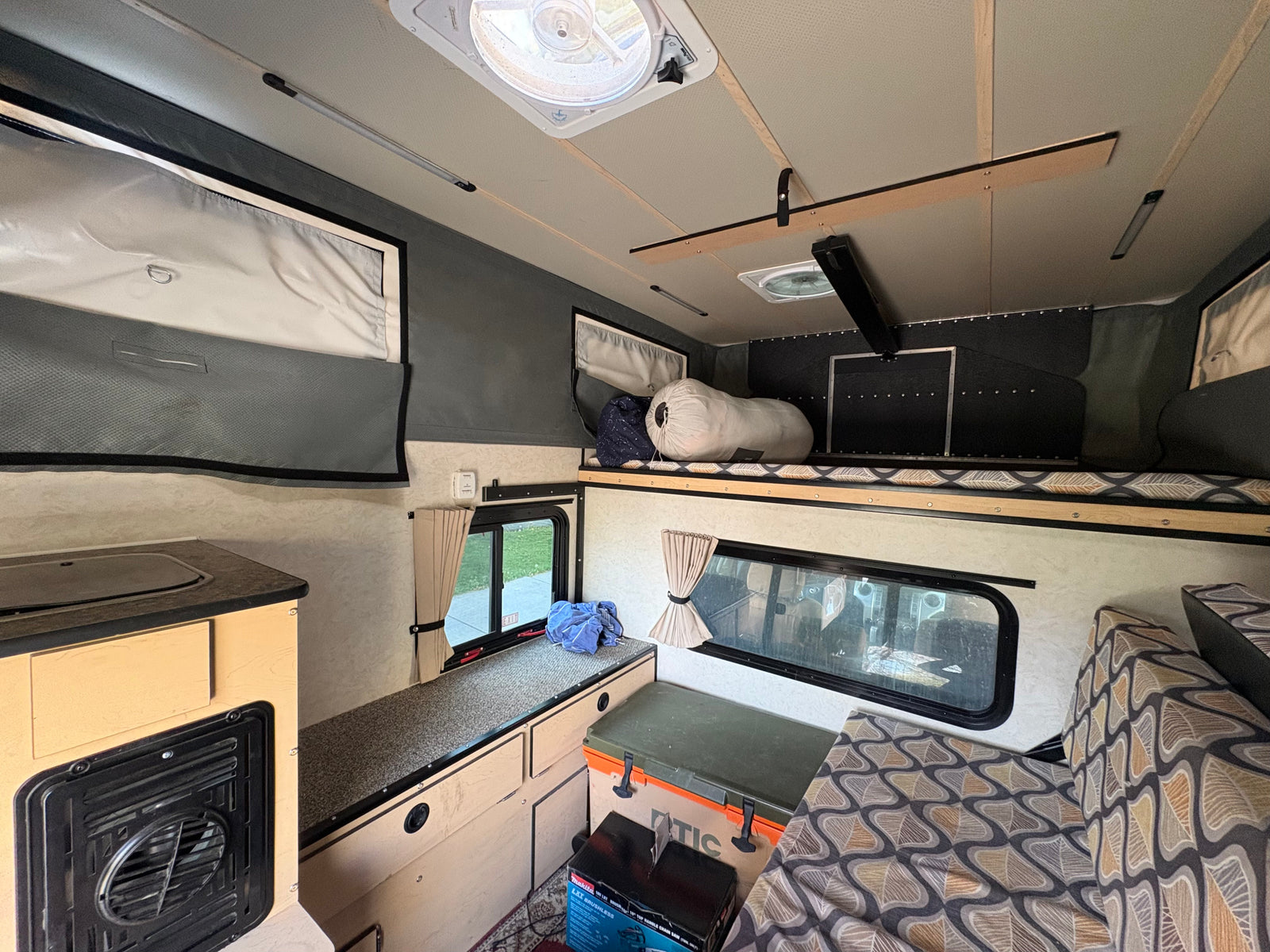 Explore this cozy RV rental interior: kitchenette, sleeping bunk, and comfortable seating for your next adventure.