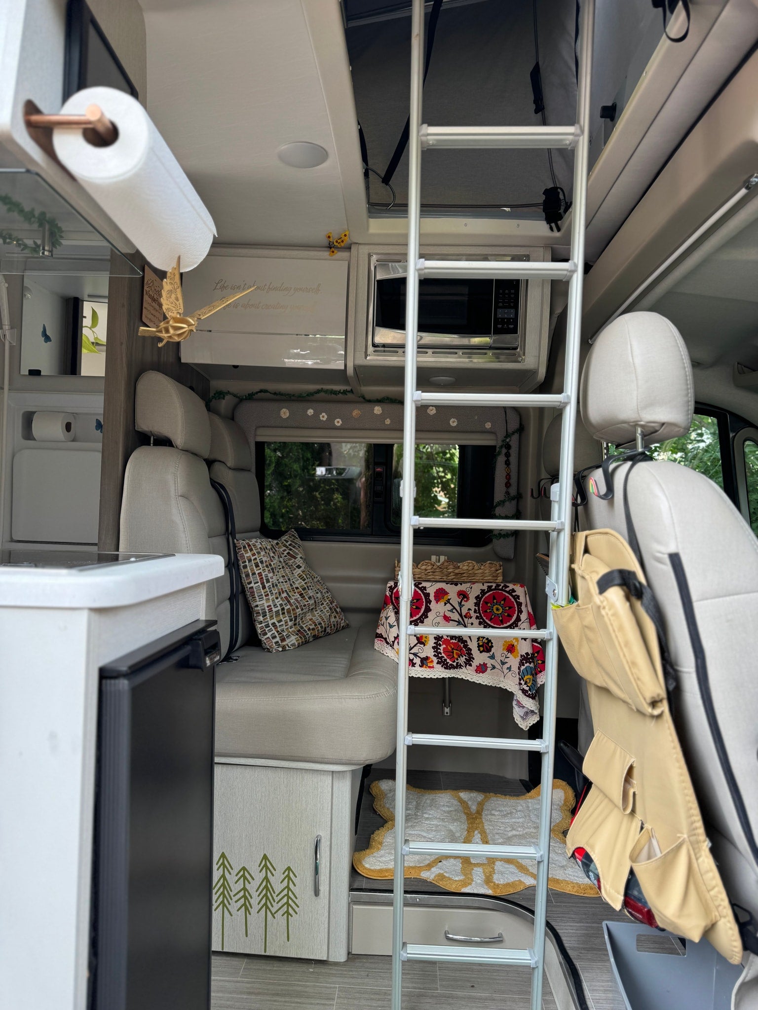 Inside a modern rv rental: clever design with kitchen, lounge, and a ladder leading to a sleeping area.