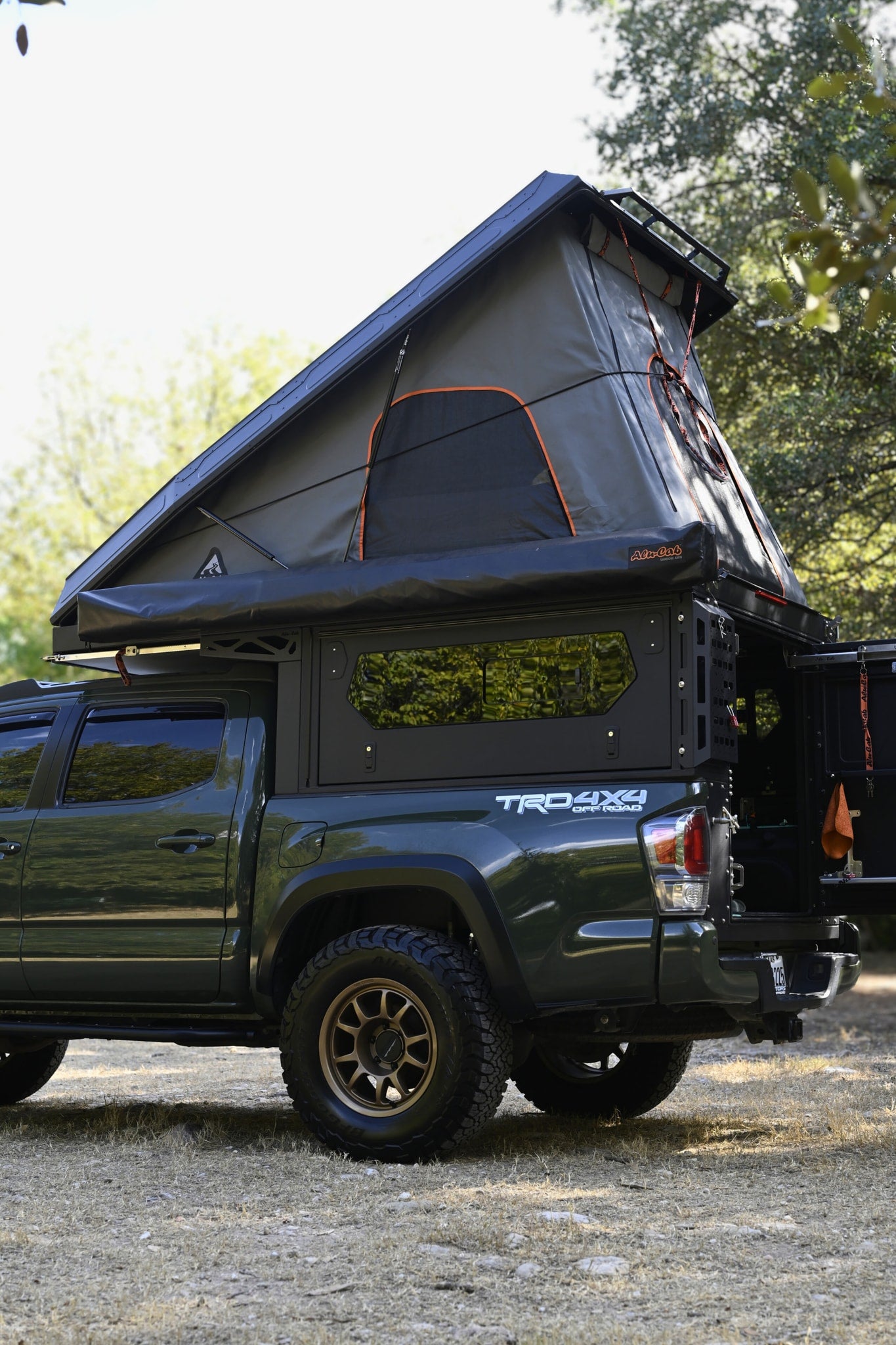 Green Toyota Tacoma truck with an open rooftop tent and camper shell. An ideal off-road rv rental for outdoor adventures.