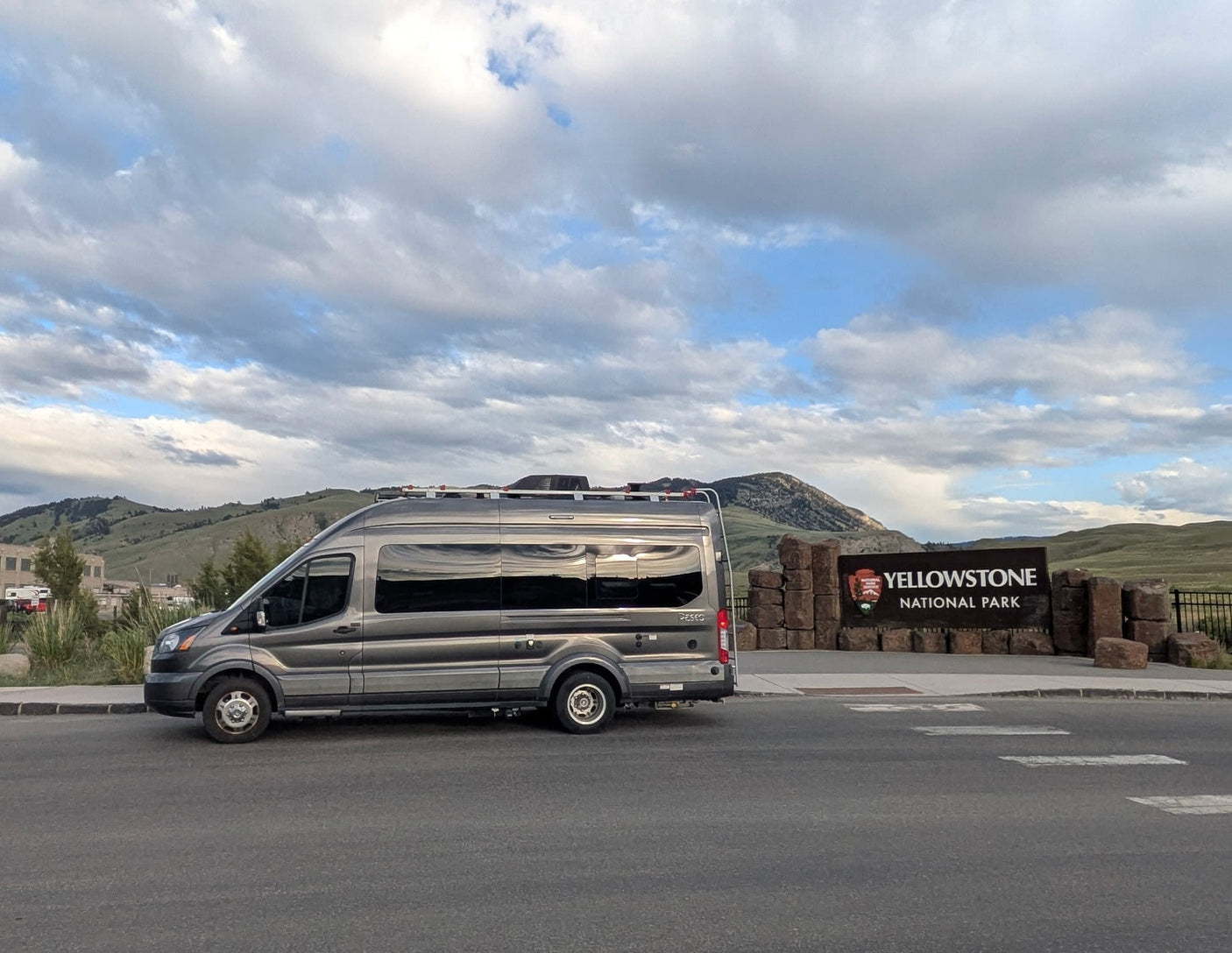 Gray RV rental van at the iconic Yellowstone National Park sign