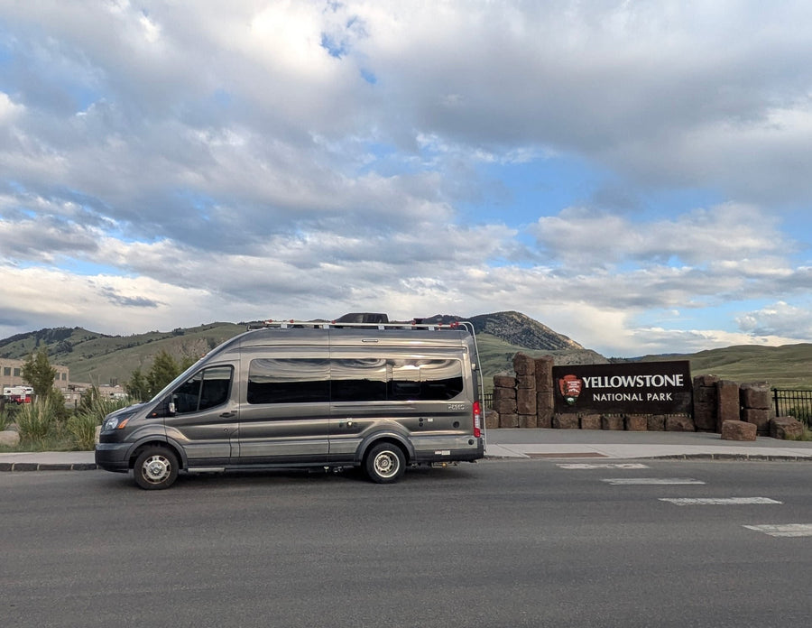 Gray RV rental van at the iconic Yellowstone National Park sign