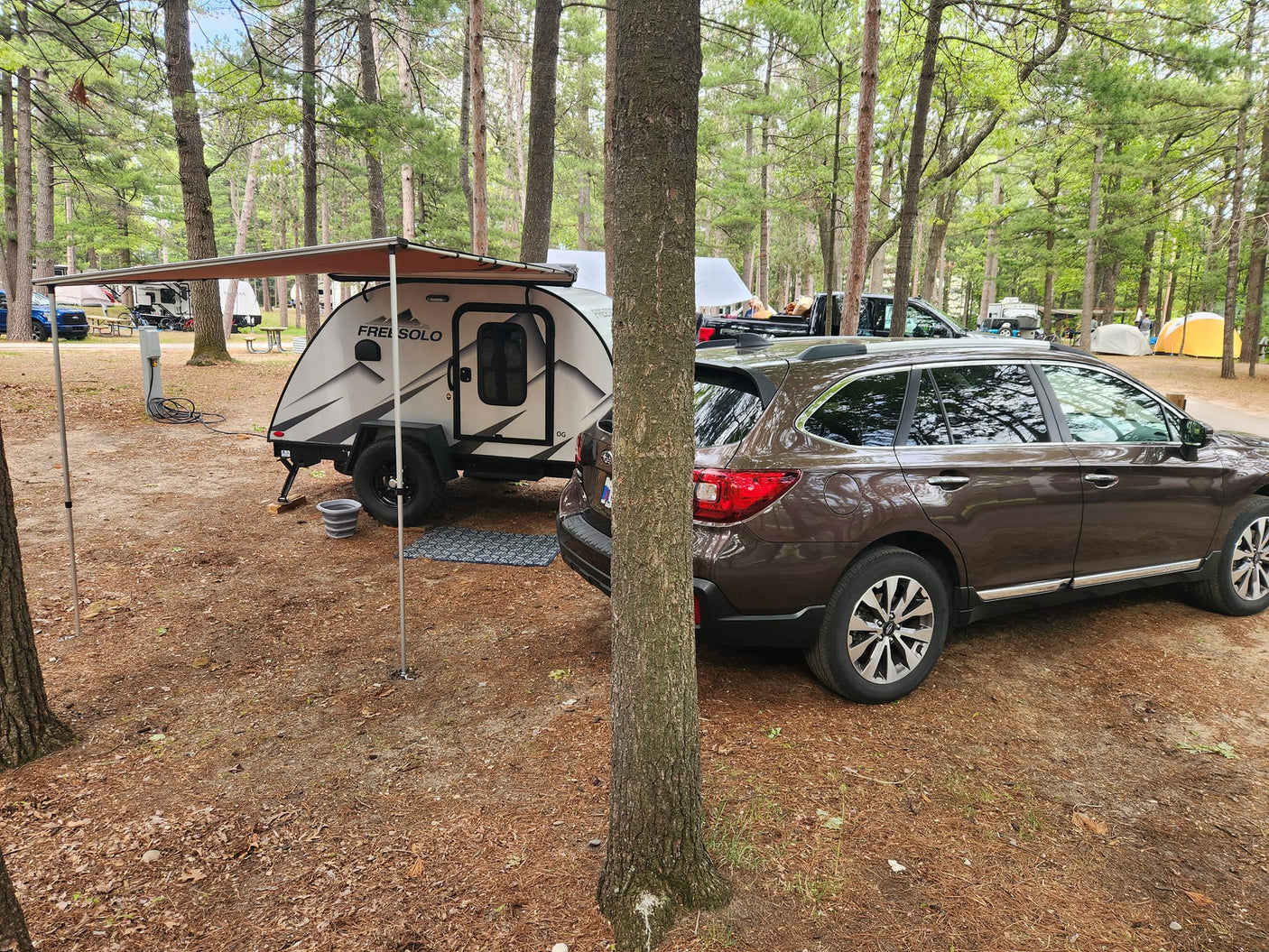 Teardrop RV rental & car at a serene forest campsite. Enjoy nature's beauty and outdoor adventure.|Outdoor kitchen of a small rv rental trailer