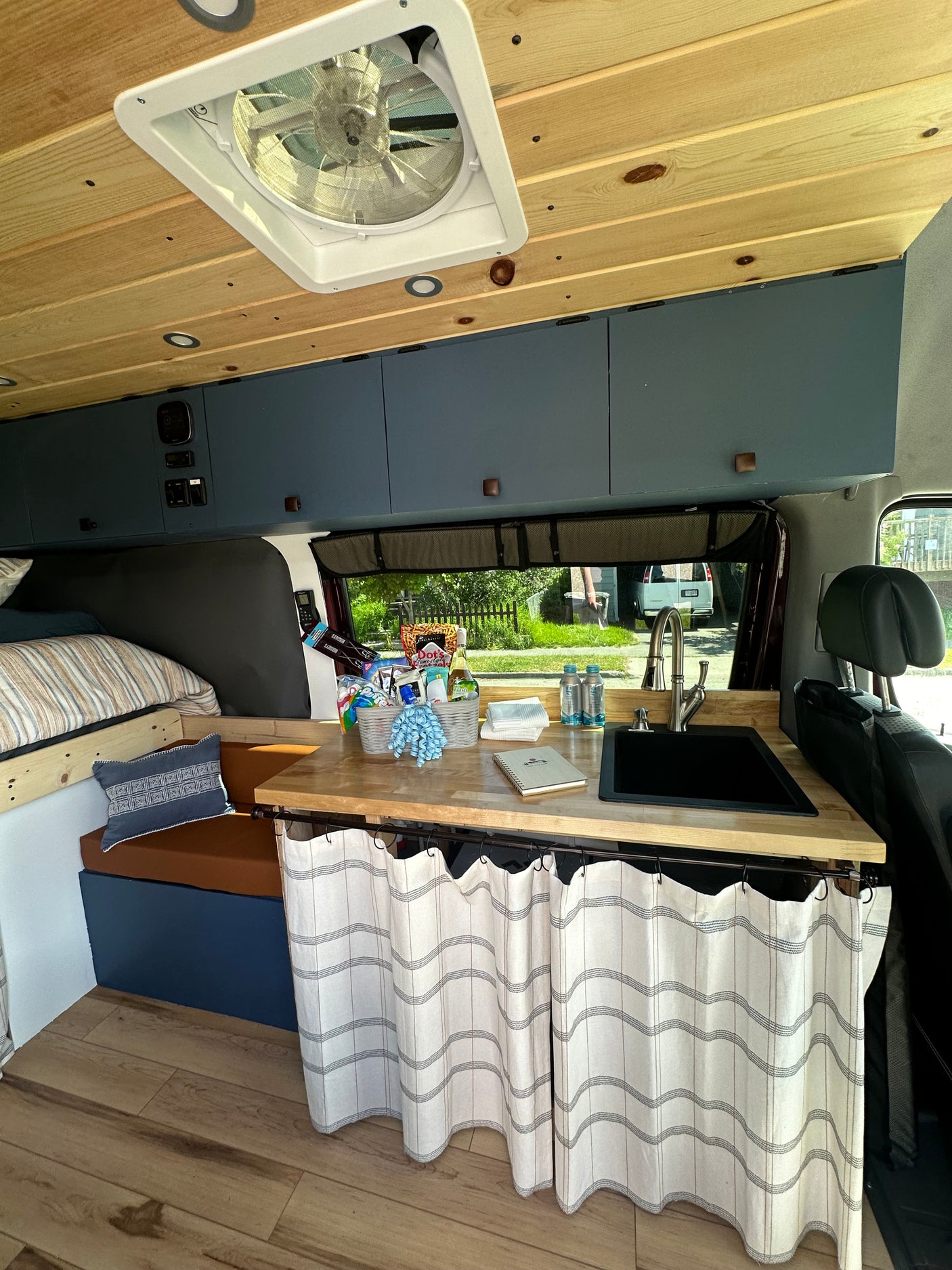 Cozy rv rental interior: wood ceiling, bed, kitchen with sink & storage. Perfect for travel adventures.