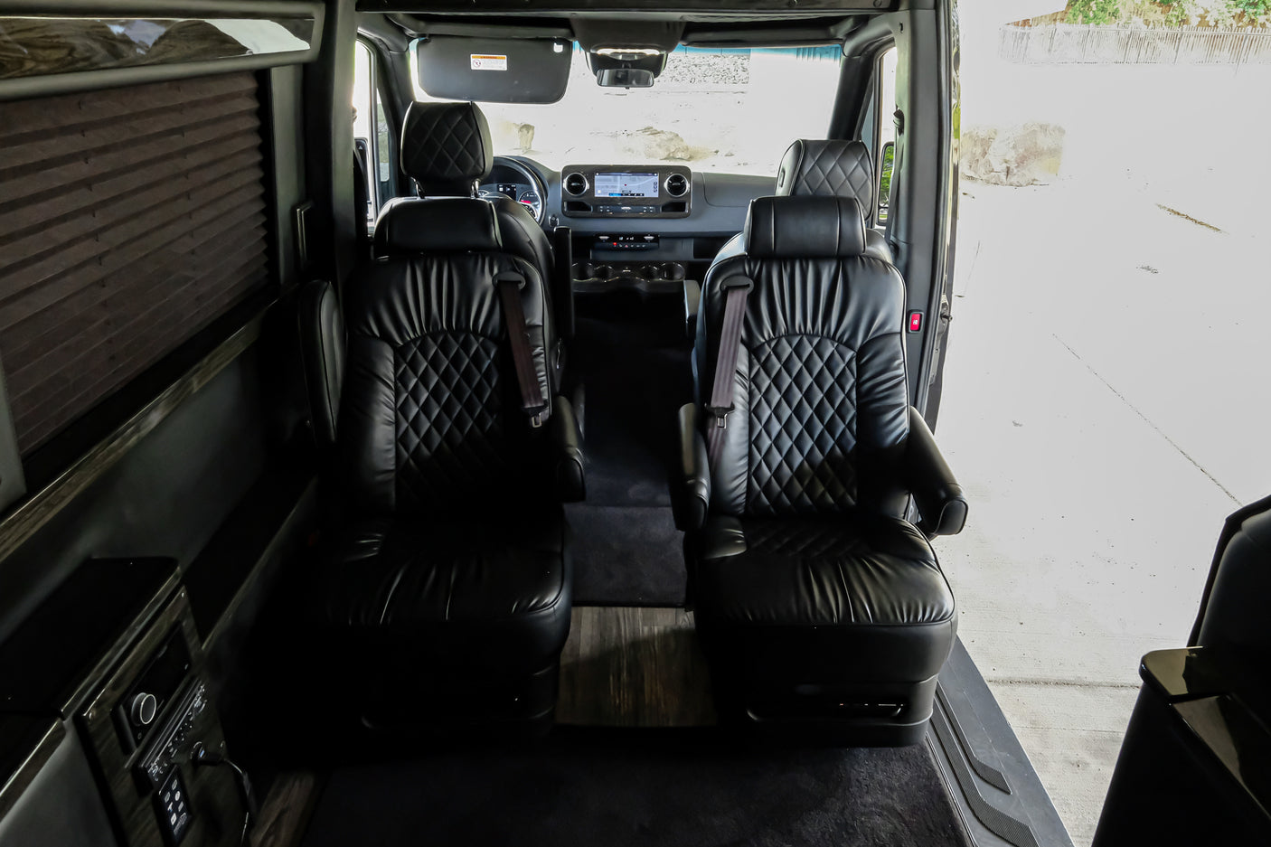 Step inside this luxury RV rental! View of plush black leather captain's chairs and modern interior amenities for comfortable travel.