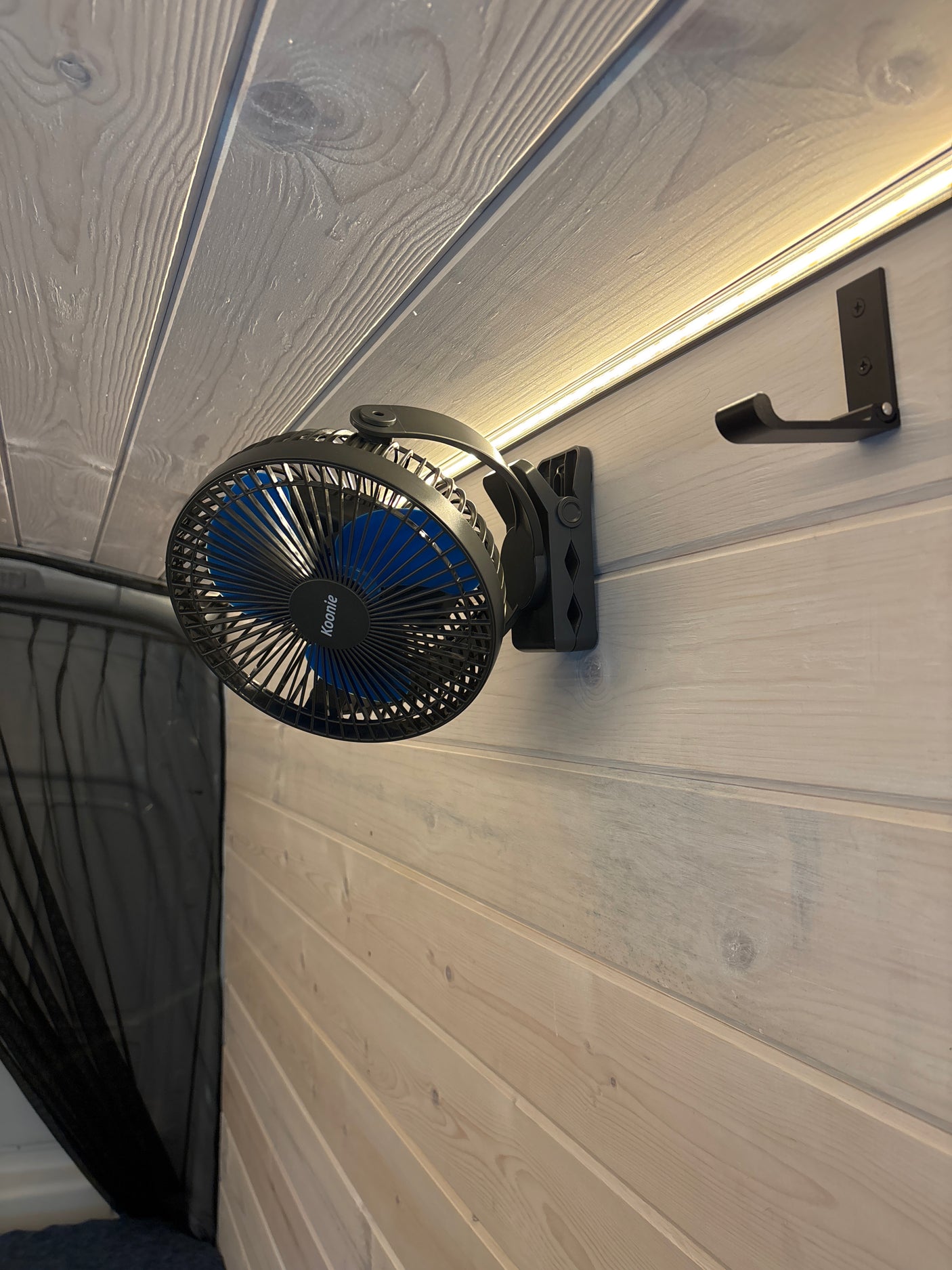 RV rental interior: A clip-on fan (Koonie) and hook on paneled walls, with LED lighting and mesh netting for comfort.
