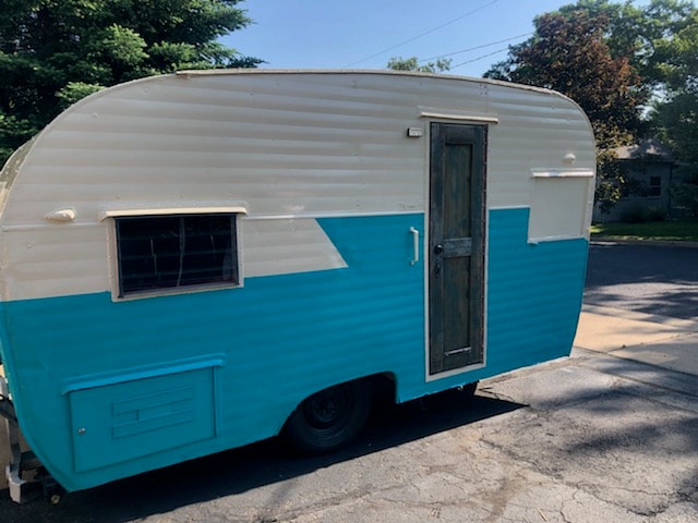 Vintage teal and white camper, ready for your next rv rental. Features side window, door, and exterior storage.