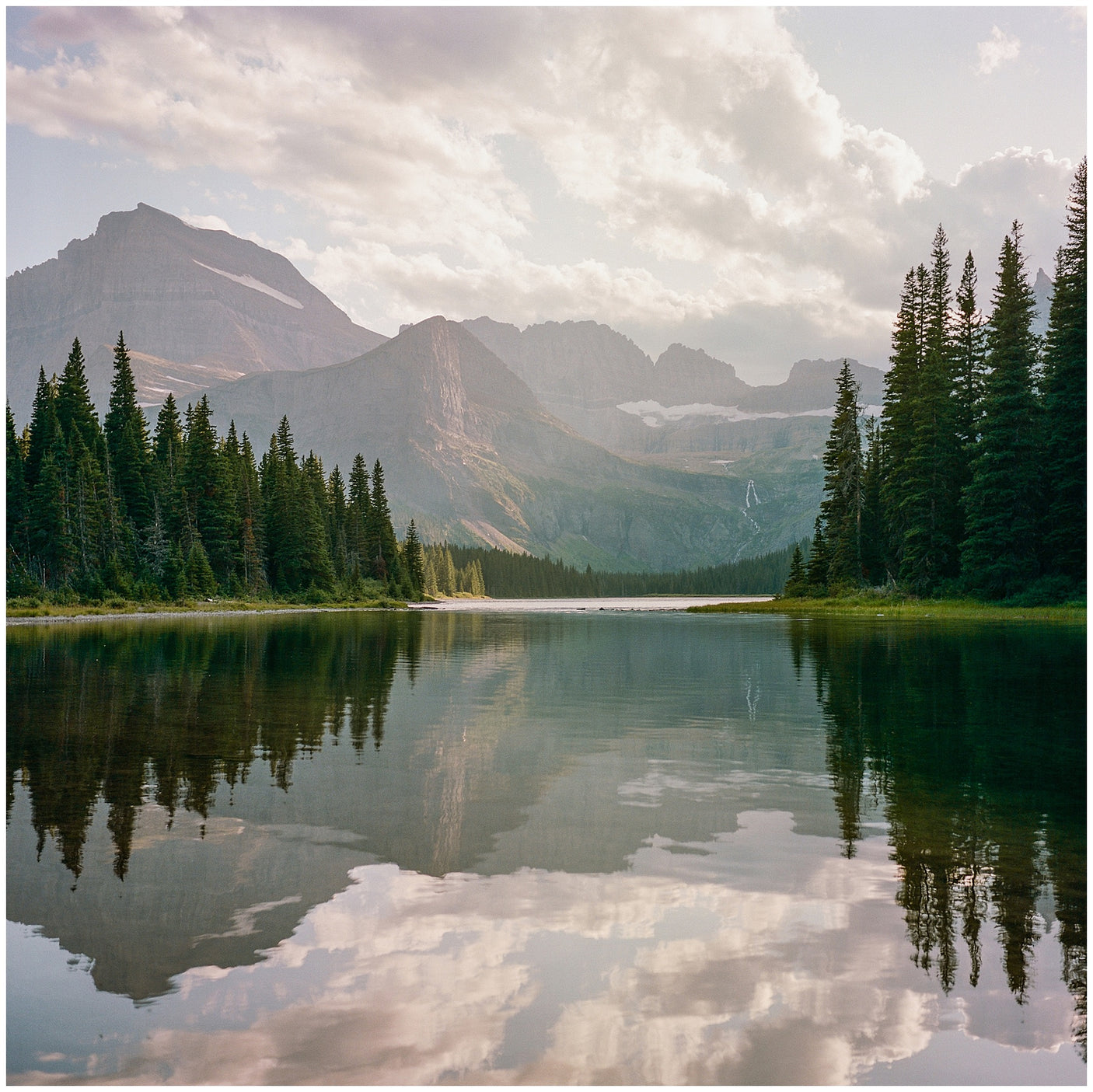 Experience serene nature: a tranquil mountain lake surrounded by dense forests & majestic peaks, ideal for an RV rental trip.