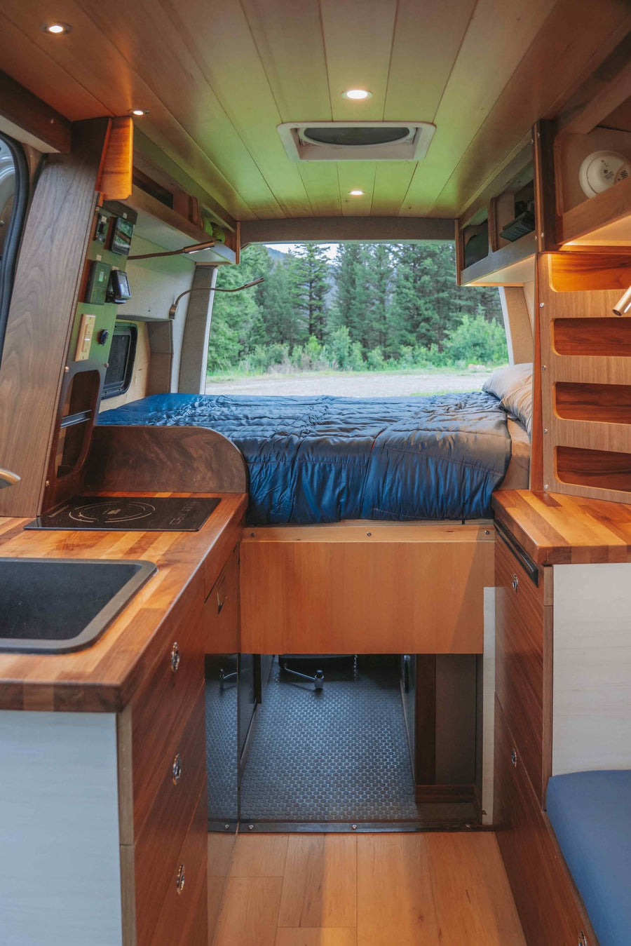 amidst trees & snow-dusted hills. Perfect outdoor travel.|Inside an rv rental: a rustic yet modern camper van with a full bed