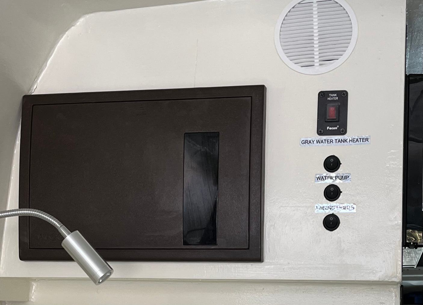 Essential RV rental control panel: Tank heater, water pump, awning lights switches, plus a flexible reading light.