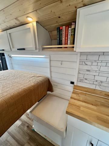 parked on a lush green hillside overlooking distant mountains.|RV rental interior: cozy bed