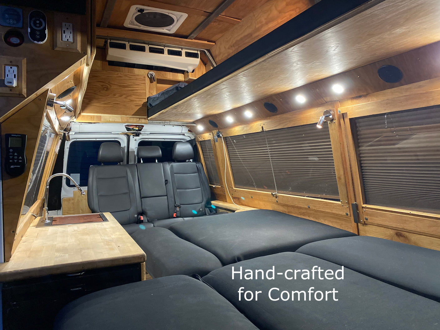 Cozy RV rental interior with custom wood trim, a functional kitchen, and comfortable bed. Hand-crafted for comfort.