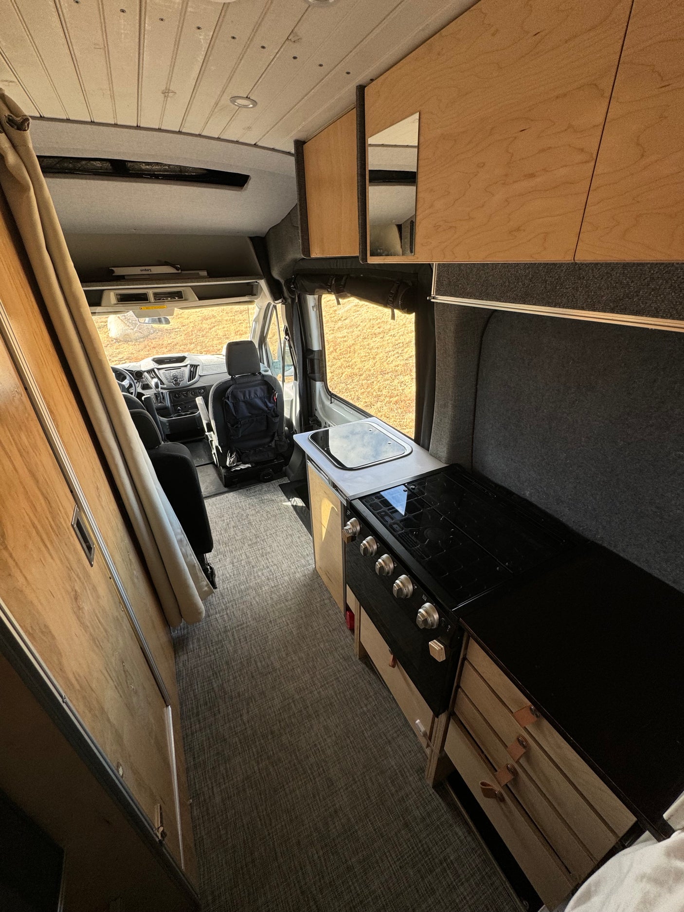 Explore this cozy RV rental interior, featuring a compact kitchen with stove & sink, ideal for road trips.