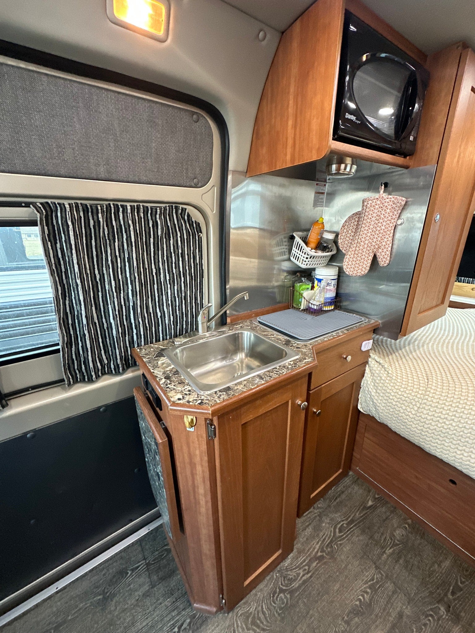 sunny sky.|Compact RV rental interior featuring a functional kitchen with sink